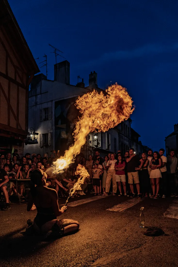 Crachage de feu dans une rue à l'heure bleue, une foule en cercle.
