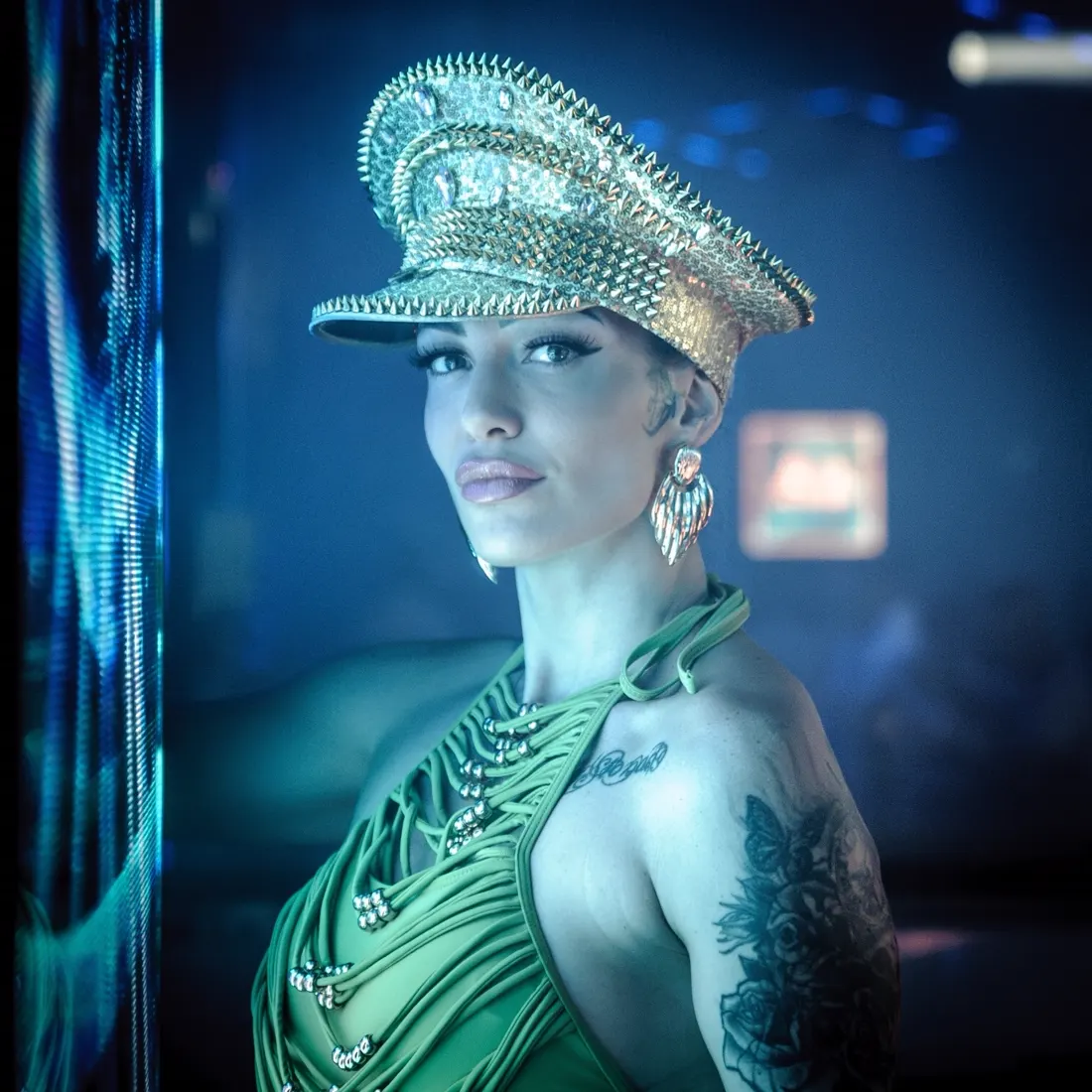 Portrait de Cyane Reyes en costume vert et casquette pailletée.