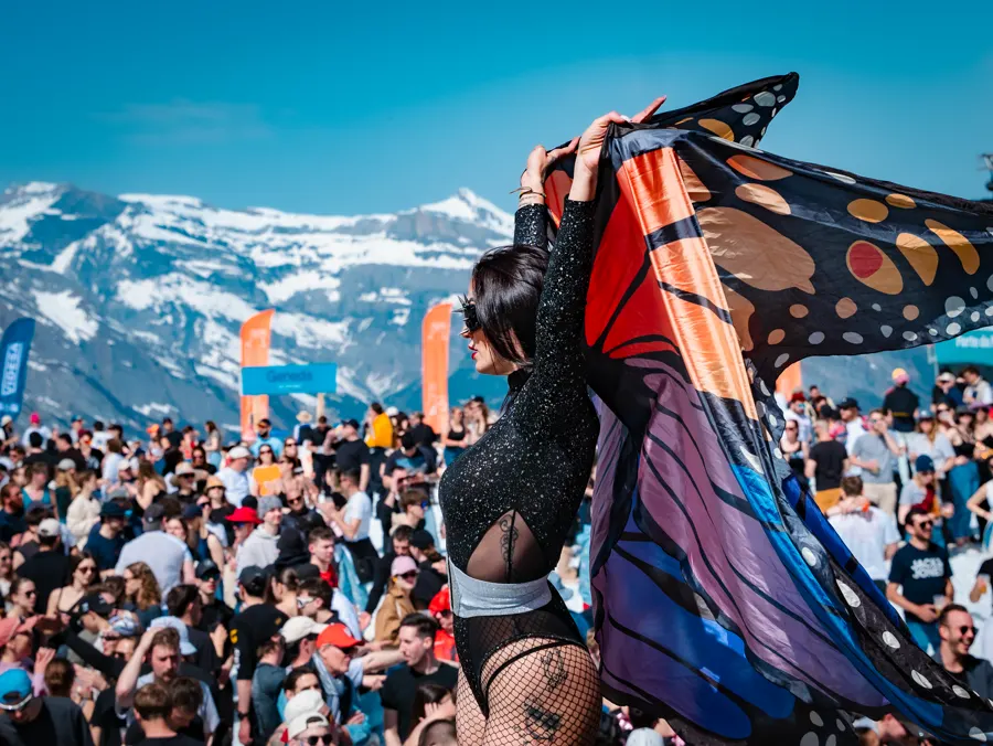 Danse avec des ailes de papillon sur une scène face aux montagnes.