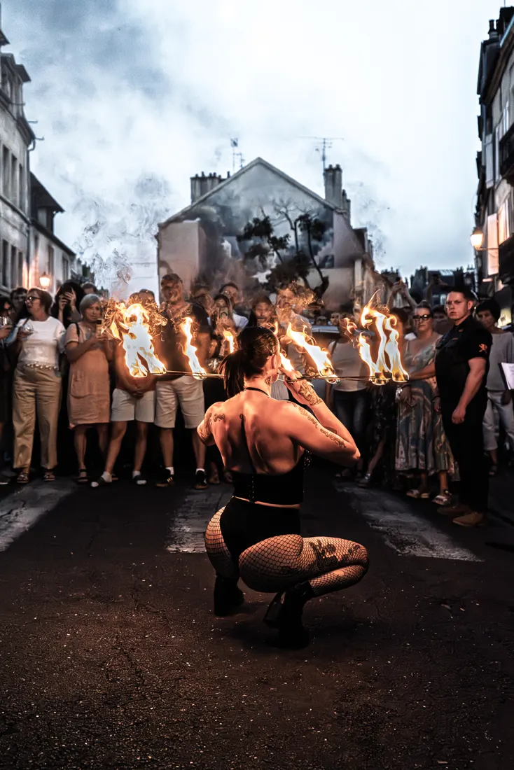 Éventails de feu face au public, dans une rue.